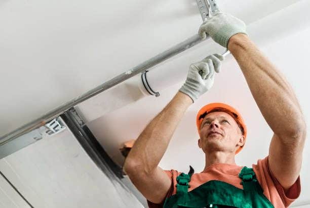 Trabajador instalando mecanismo de puerta de garaje.